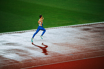 Obraz premium An intense sprinter pushing through the elements on a rainy athletics track, showcasing their athleticism and perseverance