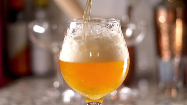 Slow Motion of craft Beer being poured in to a tulip glass, bar background