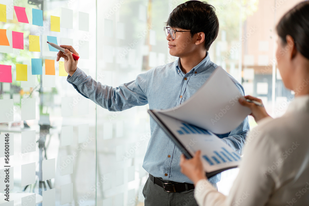 Aufkleber two business executive team holding and taking notes keyword on board wall to brainstorm about a new