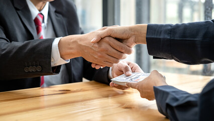 Businesspeople shaking hands to receive banknote money and terms of contract from bribe employer in...