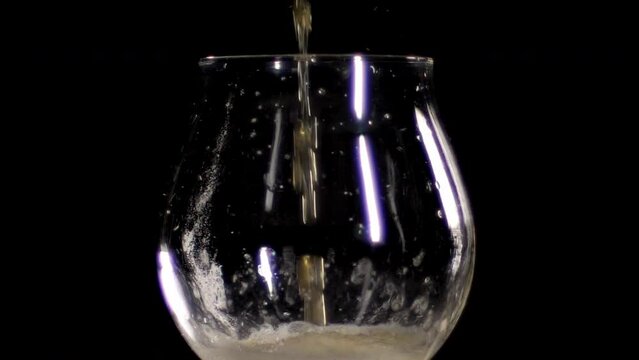 Slow Motion Close up of craft Beer being poured in to an empty tulip glass, black background