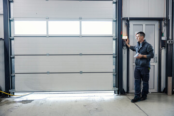 An auto-mechanic is opening garage door at mechanic's workshop.