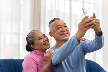 Senior couple use smartphone to selfie in living room