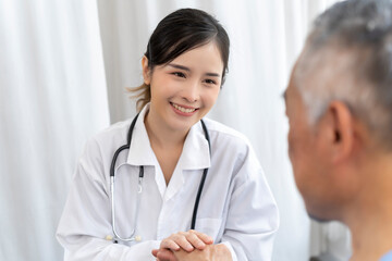 Young female doctor talking with old man in wheelchair to encourage