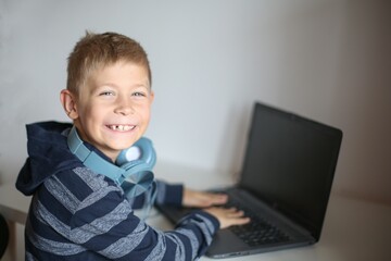 Portrait of a boy with laptop and headset at home or office