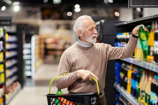 A senior man is choosing and buying sodas in supermarket.