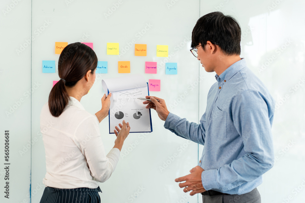 Aufkleber two business executive team holding and taking notes keyword on board wall to brainstorm about a new