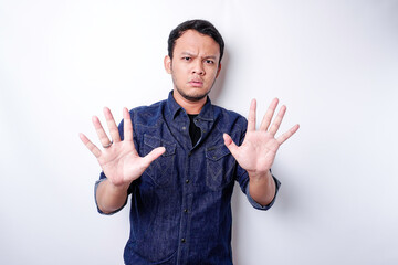 Handsome Asian man wearing blue shirt with hand gesture pose of stop or prohibition with copy space