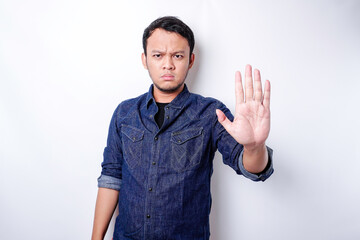 Handsome Asian man wearing blue shirt with hand gesture pose of stop or prohibition with copy space