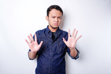 Handsome Asian man wearing blue shirt with hand gesture pose of stop or prohibition with copy space
