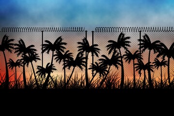 Obraz premium Barbed wire over silhouette of palm trees against sunset sky