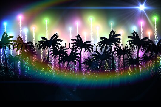 Rainbow lens flare over silhouette of palm trees against light trails against black background