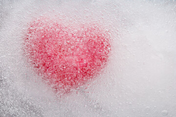 Texture of ice surface with bubbles and red frozen heart. A symbol of love or betrayal or separation.