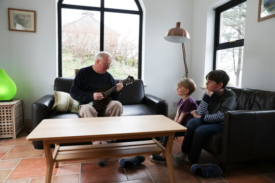 Grandfather Plays Mandolin at Home While Grandsons Listen