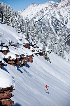 A athletic snowboarder jumping off a cliff on a sunny powder day in Colorado.