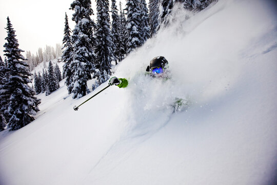 A athletic skier rips fresh deep powder turns in the backcountry on a stormy day in Colorado.