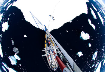 A sailboat anchors on an ice sheet while its crew explores. Located in  the west coast of Antarctica's peninsula known as Graham