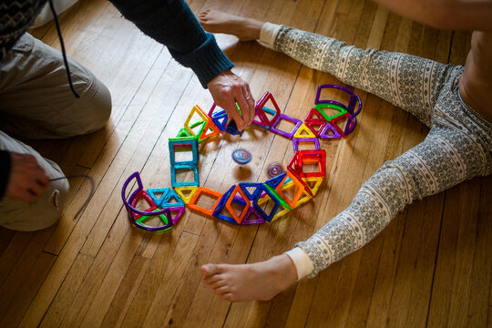 A father and child play spinning tops in a hand-constructed arena