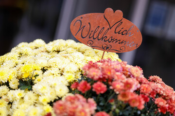 Herzlich Willkommen Schild steckt in einem Blumenstrauss