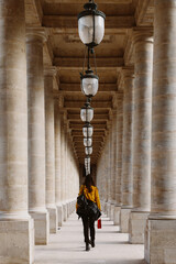 Mujer camina por un pasillo formado por columnas. 
Arquitectura París, Francia. 