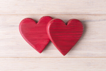 Fototapeta na wymiar Two red wooden Valentines hearts on light background. Valentine’s day concept