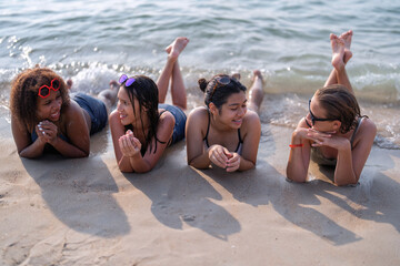Teenage girl friendship enjoy laying on beach and writing sand on blue sky day
