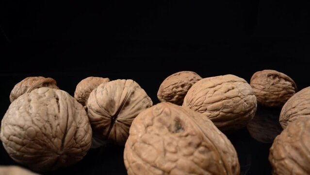Lots of whole walnuts in extreme macro shot. On a black background scattered.