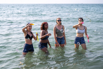 Obraz premium Teenage girl friendship enjoy stand in the sea playing soap bubble on blue sky day