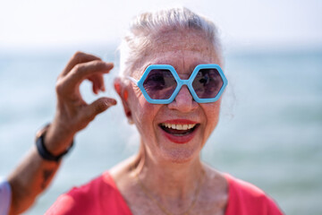 Couple of old mature people walk together on the sand at the beach enjoying and living the moment