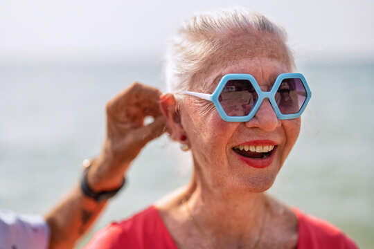 Couple of old mature people walk together on the sand at the beach enjoying and living the moment