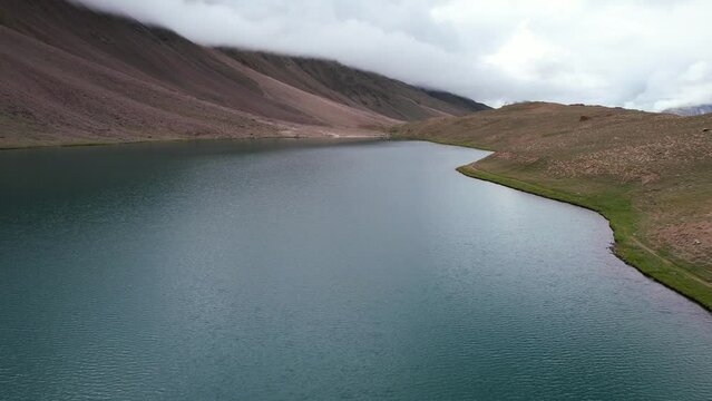 wide aerial dolly left of Chandra Taal Lake in India on cloudy day with no people