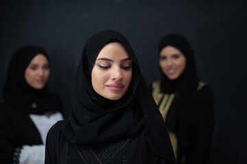 Group portrait of beautiful Muslim women in a fashionable dress with hijab isolated on black...