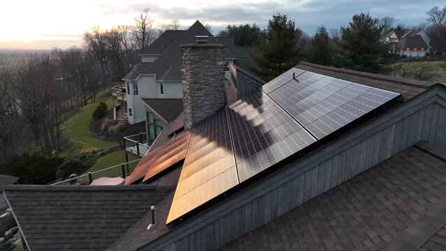 Bright golden sunlight reflecting off of clean solar panels. Beautiful aerial drone theme of solar, renewable, green energy on American house.