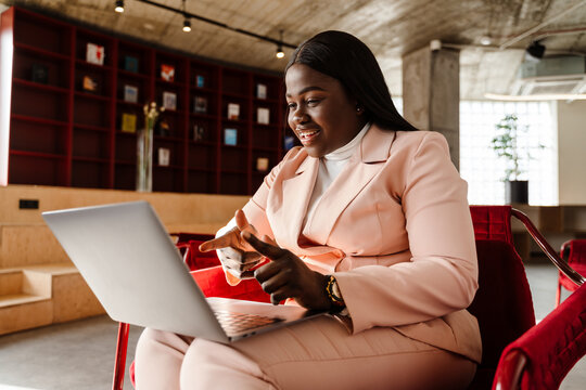 Young African American Woman In Suit Using Laptop At Office Lobby