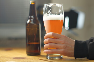 person holding a mug with beer on the table