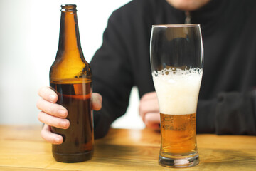 person holding a bottle with beer on the table