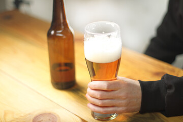 person holding a beer mug next to a bottle