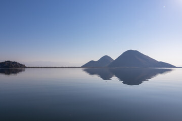 Scenic view of Lake Skadar National Park in autumn near Virpazar, Bar, Montenegro, Balkans, Europe. Hills striking out with Dinaric Alps in back, Albania. Stunning landscape water reflection in nature