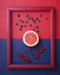 Grapefruit, blueberry, currant in frame on red and blue