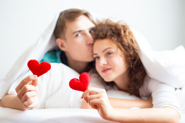 Obraz na płótnie Canvas Love couple lying on white bed blanket hold heart symbol