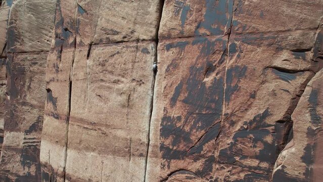 Aerial View of Man Climbing on Steep Vertical Cliff. Climber and Ropes on Vertical Rock, Drone Shot