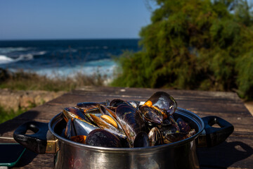 Cooked mussels in a pot in nature overlooking the ocean
