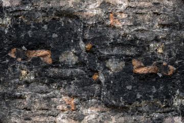 Abandoned burned old brick wall with damaged plaster