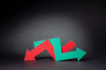 Indecision in the stock or crypto market. Red and green arrows intertwined on black background. Economic growth or global recession.