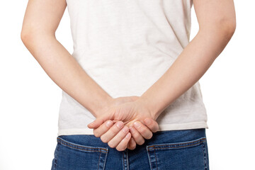 Cropped shot of a young woman back turned holding hands behind back in blue jeans on white...