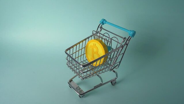 3D Bitcoin token made out of real paper getting in of a shopping cart, buying or selling crypto on a flat background
