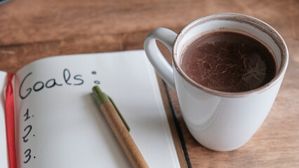 Taza de chocolate caliente con una libreta de planificación de logros