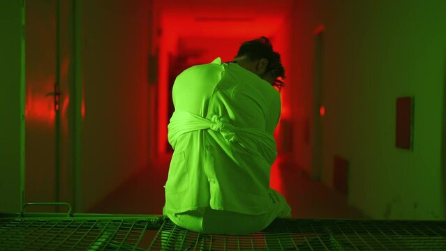 A mad male patient in straitjacket is going crazy in a mental hospital. Mentally ill man with psychic disorders and bipolar disease. Concept of paranoia or schizophrenia and madness or depression.