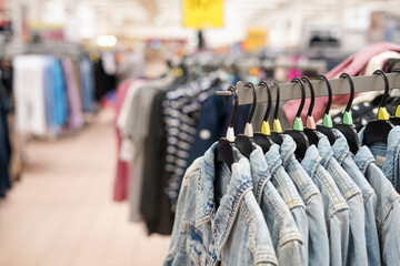 Women's clothes Jean jackets on hangers in a retail shop. Fashion and shopping concept