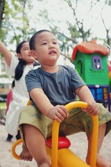 Fototapeta na wymiar Happy asian kids playing seesaw at playground. Cute kids having fun on seesaw at playground.